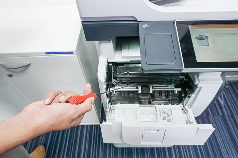 Man with screwdriver in hand fix printer